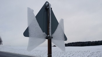 Traffic Sign with Angel Wings (back) / Looking at the back side of the traffic sign you can understand what happened here. The snow had been sticking to the back of the traffic sign and before freezing it partially melted creating a thin ice layer. During the next day this ice had been melting while still sticking a little bit to the downside. And this way the angel spread its wings!