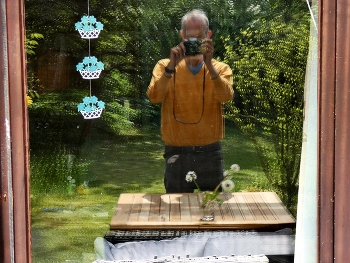 Der Fotograf, die Kamera, das Motiv auf dem Tisch / Eine Spiegelung in der Terrassentür