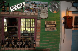 Bar in Namibia / Eine Bar in einer Lodge in Namibia. Neben dem zerbrochenen Fenster mit den Schnaps- und Bierflaschen hängt ein uraltes Telefon. Vermutlich funktioniert es nicht mehr, wenn man anfängt, alle doppelt zu sehen. Den Arzt kann man damit also nicht rufen. Ist ja vielleicht auch zu weit entfernt. Aber wofür gibt es Mobiltelefone? De funktionieren womöglich auch im Busch.