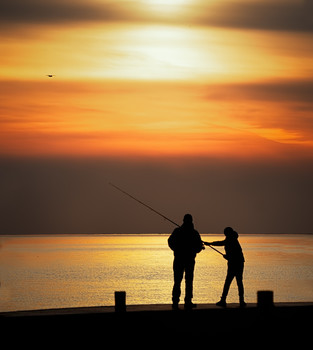 &nbsp; / Father and son fishing off of a pier at sunset.